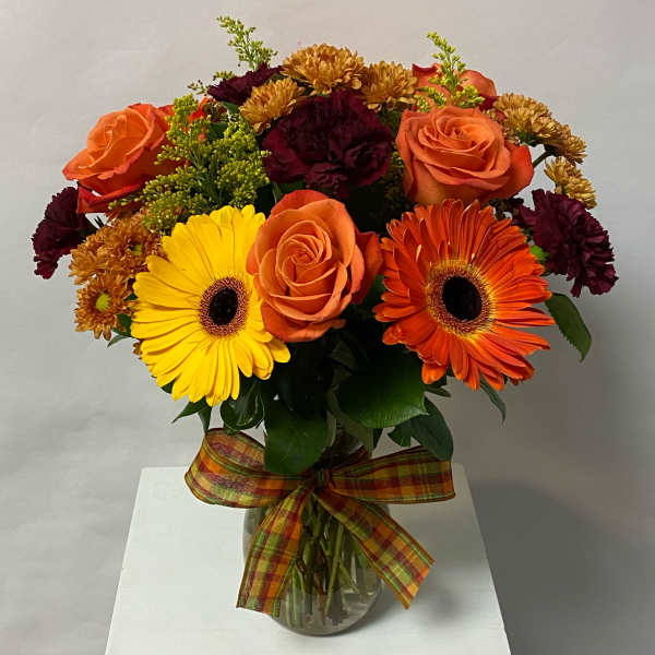 Bouquet of orange roses, gerbera daisies, and mums in a glass vase