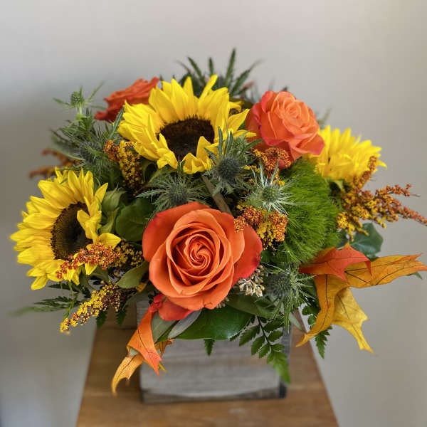 Orange roses and yellow sunflowers in a square container