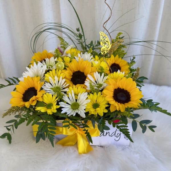 Yellow sunflowers and white daisies in a ribboned gift box