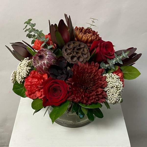 Red and burgundy floral arrangement in a clear glass vase