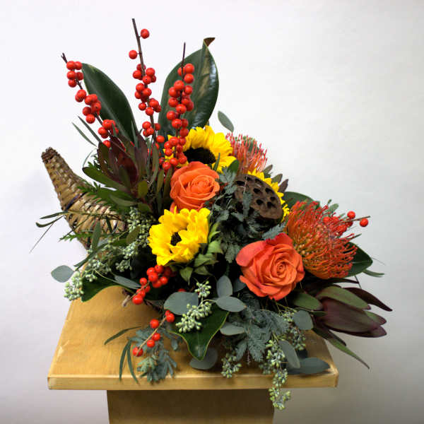 Mixed floral arrangement with sunflowers, orange roses, and red berry stems