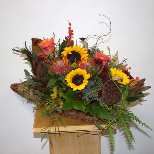 Mixed bouquet with sunflowers and orange roses in a woven basket