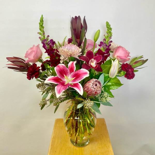 Mixed pink and burgundy flowers in a clear glass vase