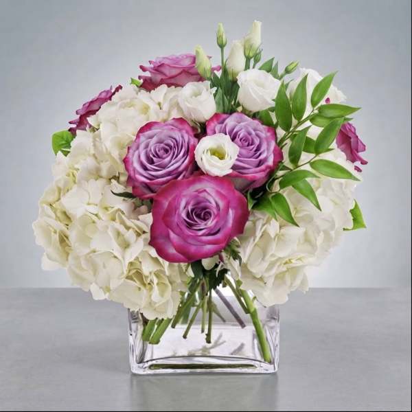 Pink and white rose bouquet in a clear square vase