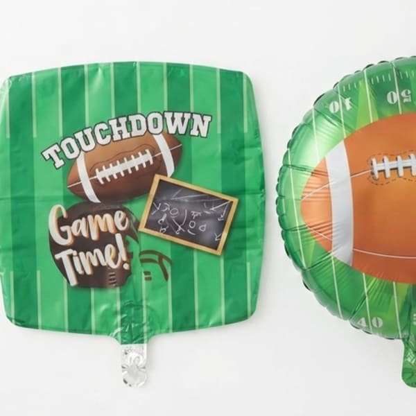 Two green football-themed foil balloons on a white background.