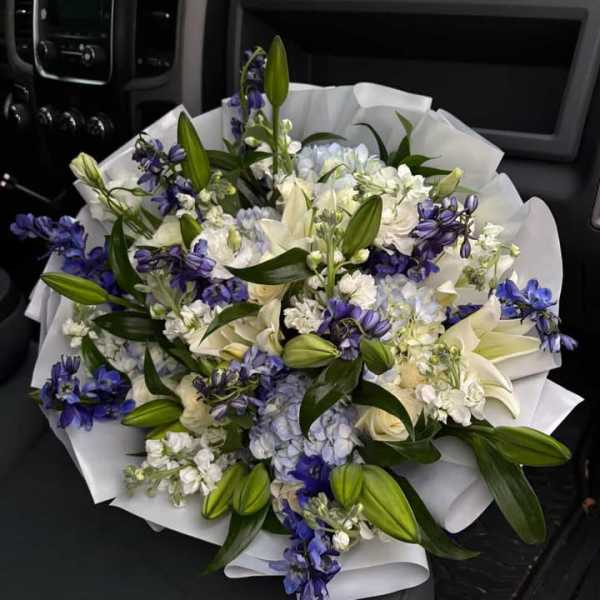Bouquet of white lilies, blue flowers, and pale hydrangeas