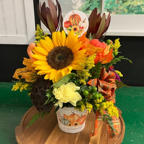 Fall floral arrangement with a sunflower in a pumpkin-themed pot