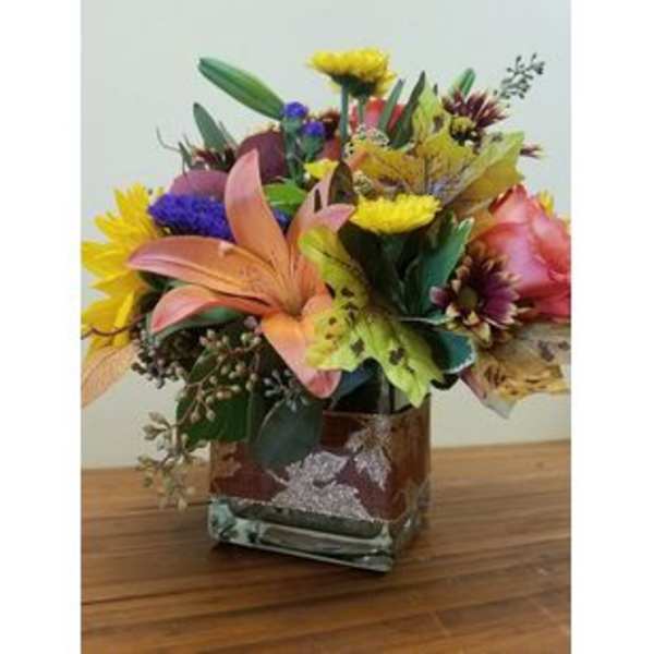 Mixed bouquet in a square glass vase with lilies and bright blooms