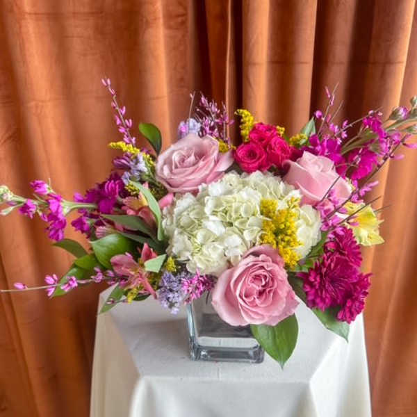 Pink and white rose arrangement in a square glass vase