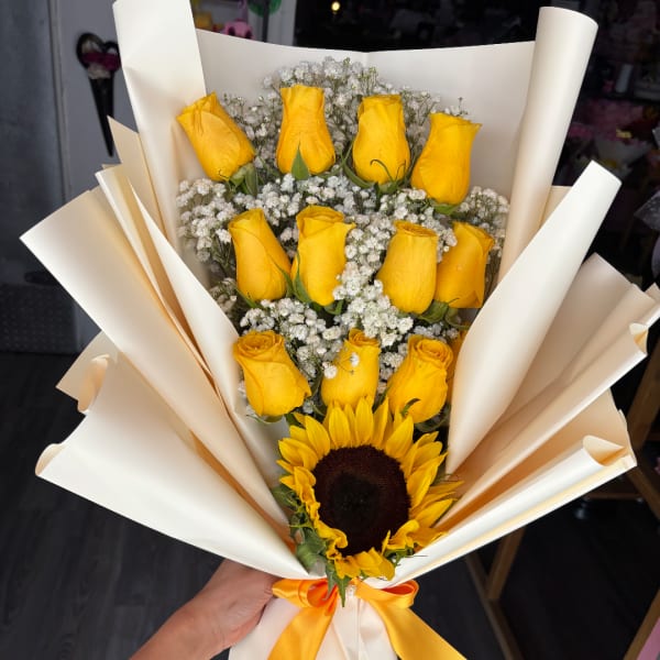 Bouquet of yellow roses and a sunflower wrapped in cream paper