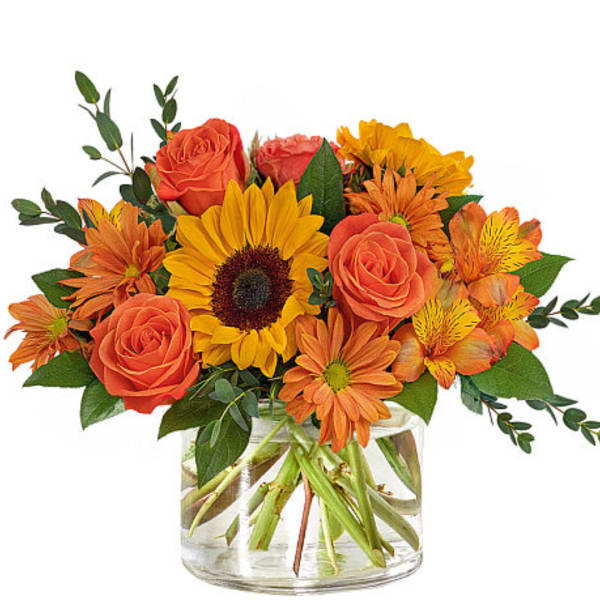 Orange roses and sunflowers in a clear glass vase