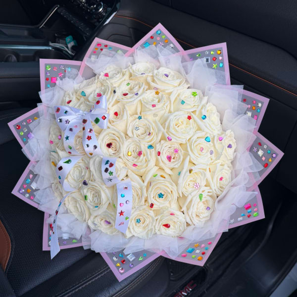 Bouquet of white roses wrapped in pink paper with a white ribbon