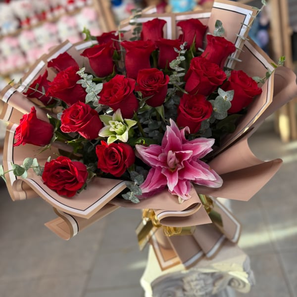 Bouquet of red roses with a pink lily in tan wrapping