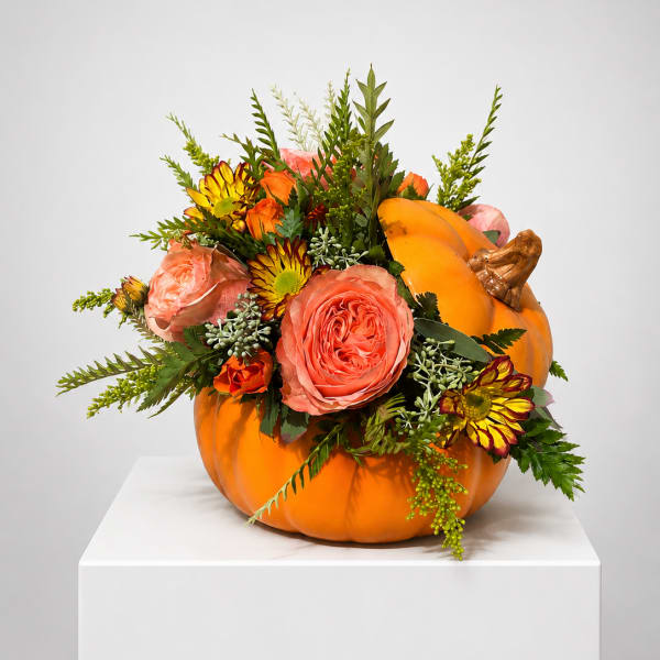 Orange pumpkin filled with pink and yellow flowers