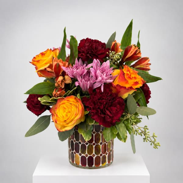 Colorful bouquet of roses, carnations, and chrysanthemums in a mosaic glass vase