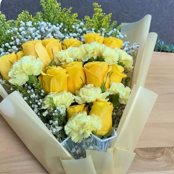 Yellow roses and pale yellow carnations in cream wrapping