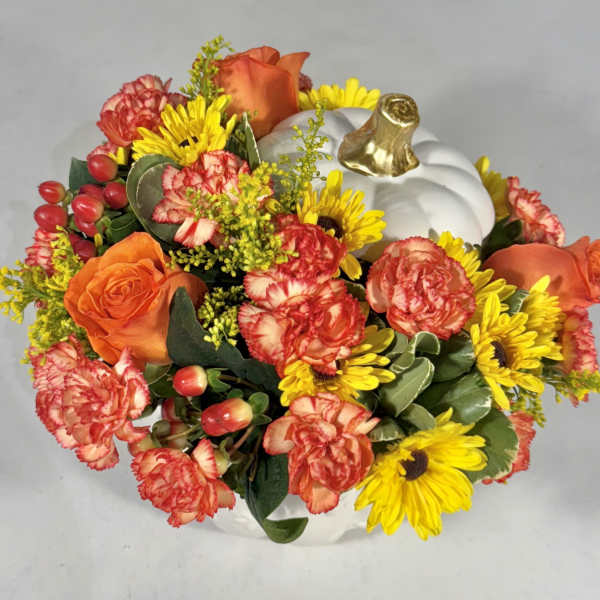 Orange roses and yellow daisies arranged in a white pumpkin container