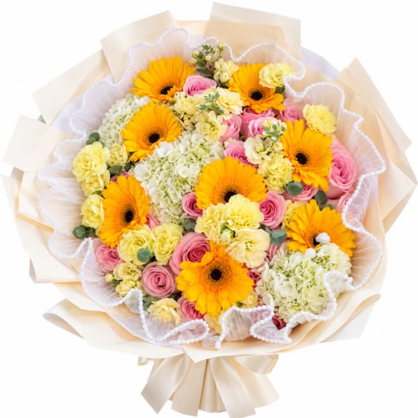 Bouquet of yellow gerbera daisies, pink roses, and pale carnations wrapped in cream paper