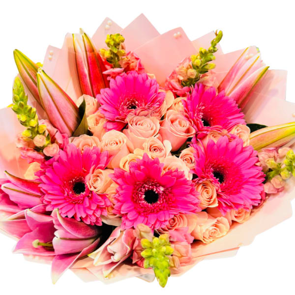 Pink bouquet with gerbera daisies, roses, and lilies wrapped in pale paper