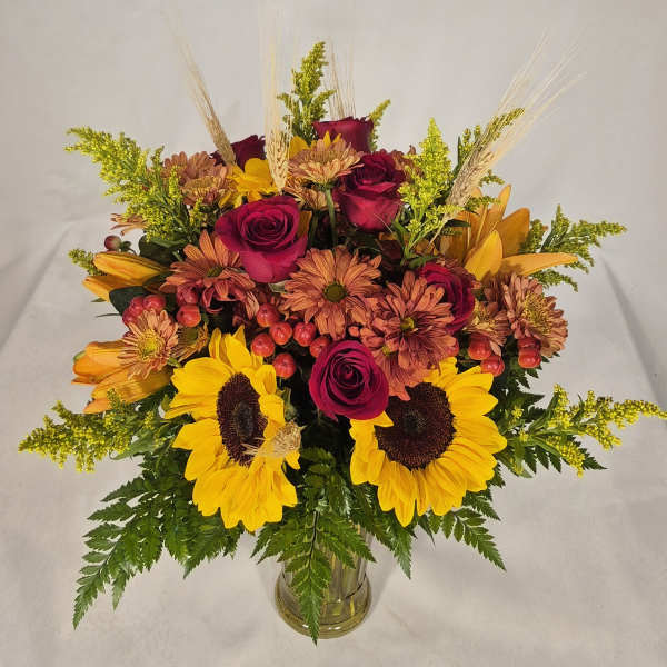 Bouquet of sunflowers, roses, and mums in a clear glass vase