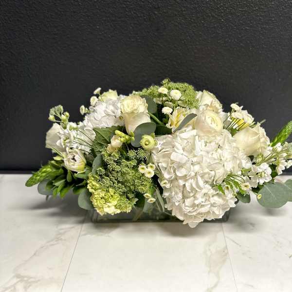 Low white floral arrangement in a rectangular glass vase