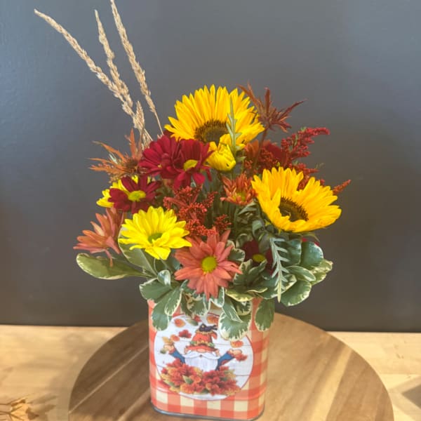 Fall bouquet with sunflowers and daisies in a decorative tin container