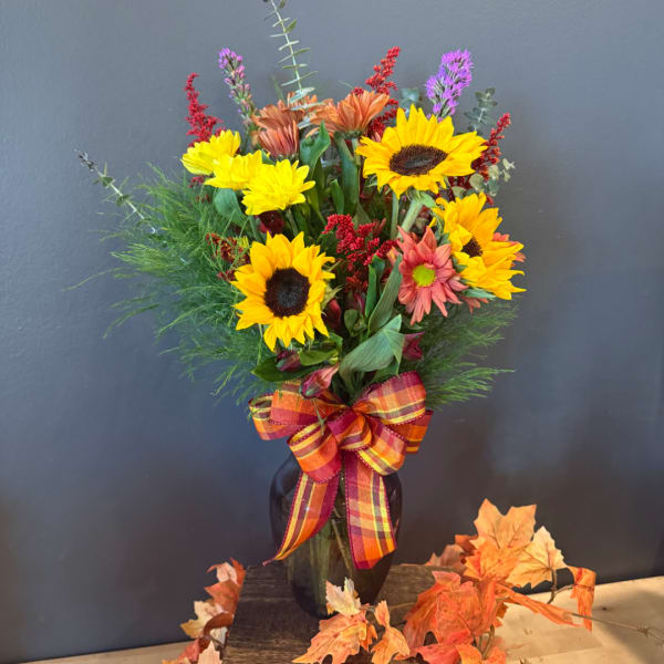 Sunflower bouquet in a dark vase with a plaid ribbon