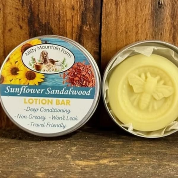 Two round tins of sunflower sandalwood lotion bar on a wooden surface.