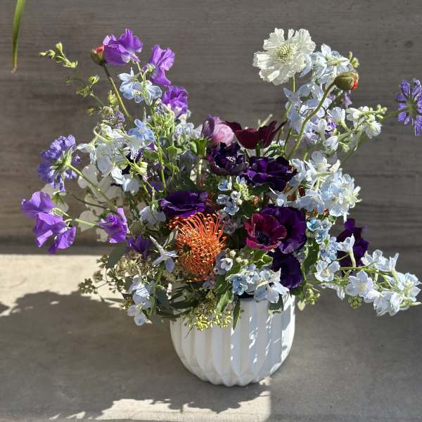 Mixed purple and white flowers arranged in a white vase