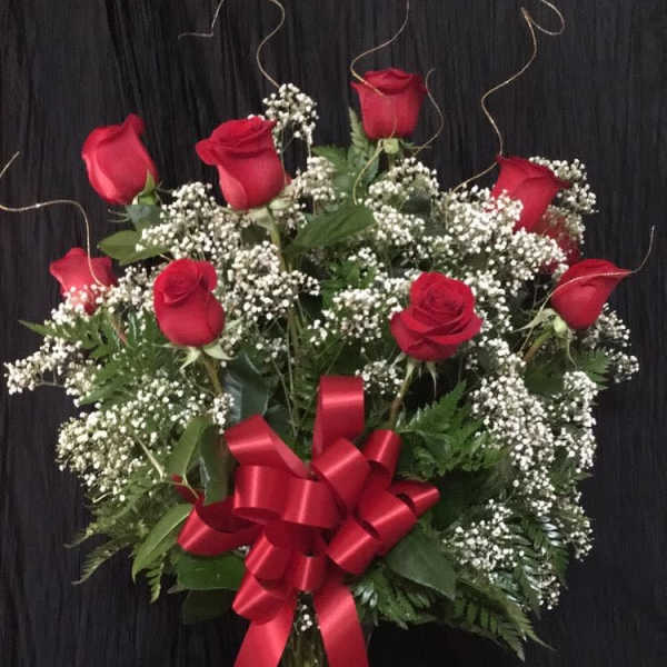Red roses and baby's breath in a glass vase with a red bow