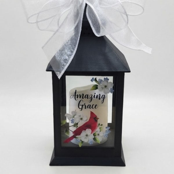 Black lantern with a white bow and a candle labeled Amazing Grace