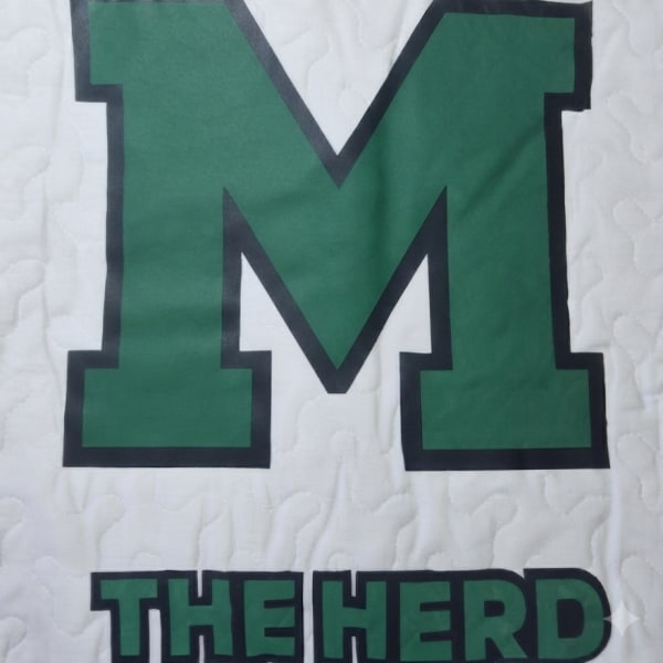 Green letter M with the words THE HERD on a white quilted background