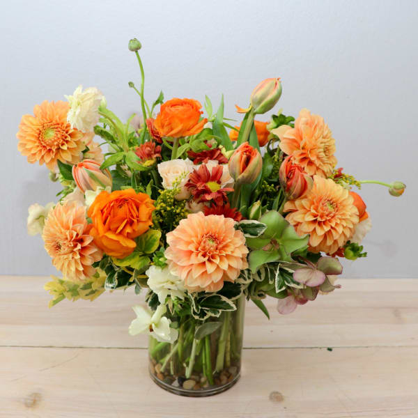 Orange and peach mixed bouquet in a clear glass vase
