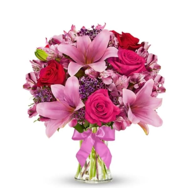 Pink and red flower bouquet in a clear glass vase with a ribbon