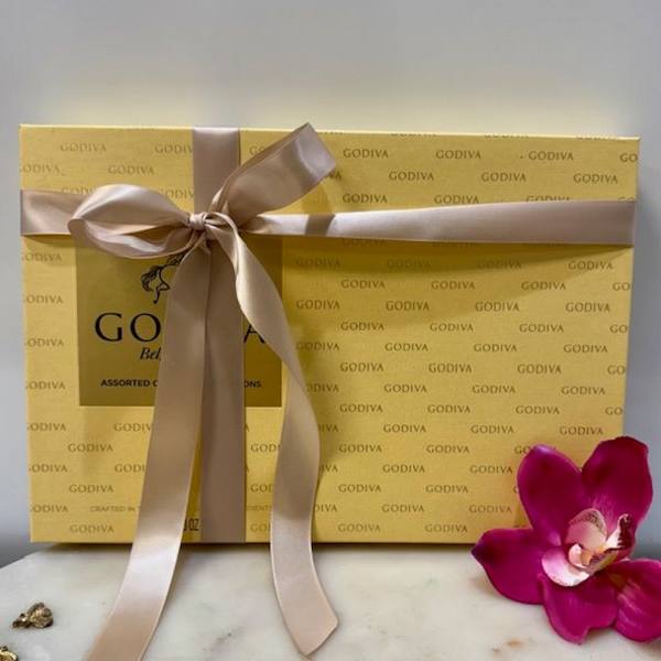 Gift box of Godiva chocolates tied with a satin ribbon and orchid bloom