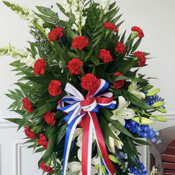 Large standing floral spray with red carnations, white lilies, and blue flowers