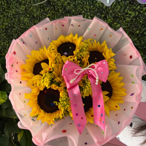 Bouquet of sunflowers wrapped in pink paper with a satin bow