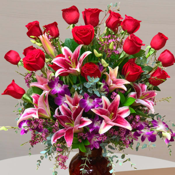 Large bouquet of red roses and pink lilies in a brown glass vase