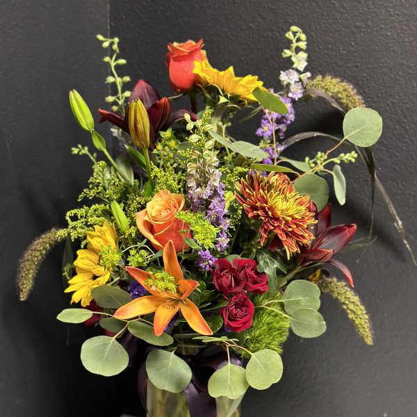 Mixed bouquet in a glass vase with roses, lilies, and sunflowers