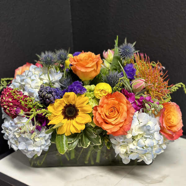 Colorful mixed flower arrangement in a rectangular glass vase
