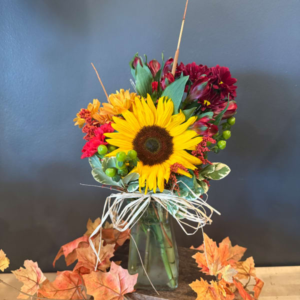 Sunflower bouquet in a glass vase with orange and burgundy flowers