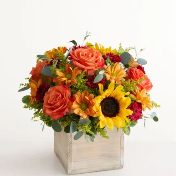 Mixed bouquet with roses, sunflowers, and daisies in a wooden box