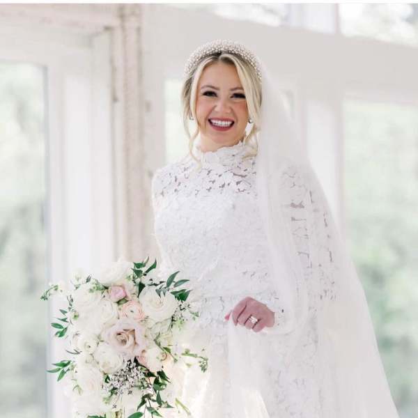 Bride in a white lace gown holding a cascading bouquet of white and blush flowers
