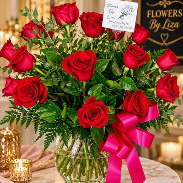Red roses in a glass vase with a pink ribbon