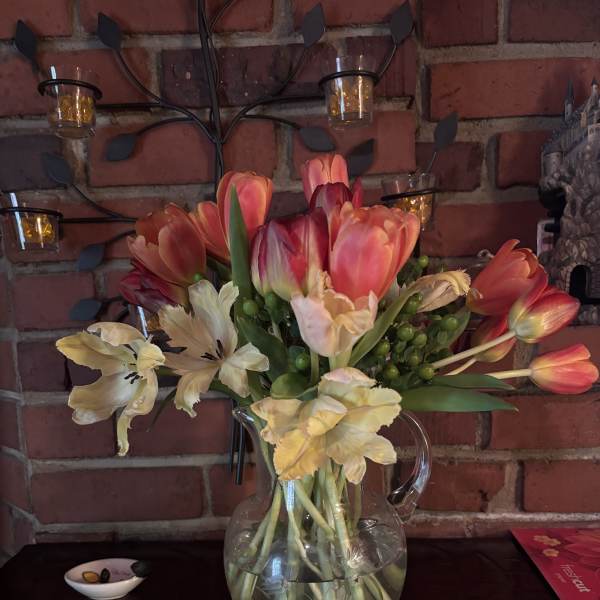 Tulip bouquet with pale cream flowers in a clear glass pitcher vase
