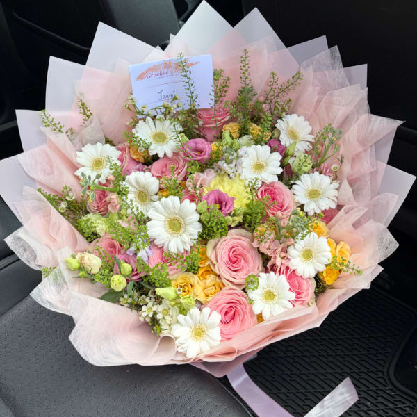 Pink and white mixed bouquet with daisies and roses wrapped in pale pink paper