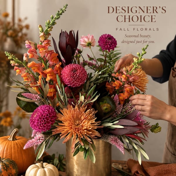 Fall floral arrangement in a gold vase with orange, pink, and burgundy blooms