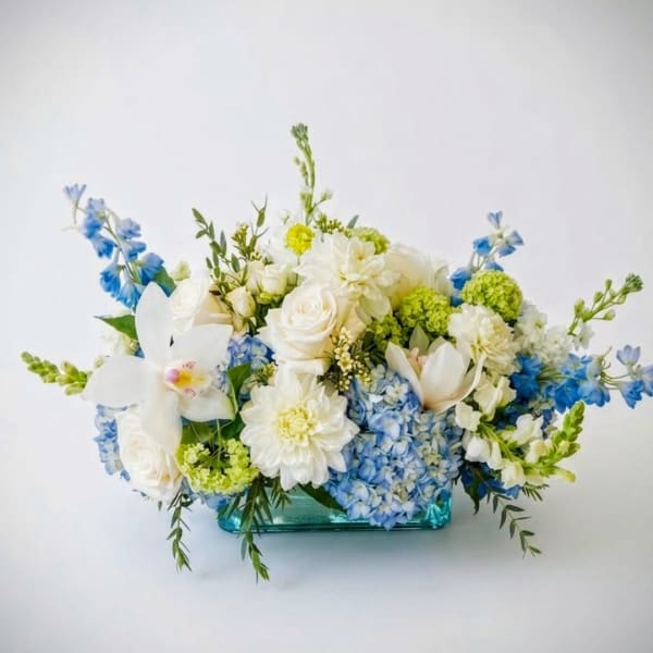 Blue and white floral arrangement in a turquoise glass vase