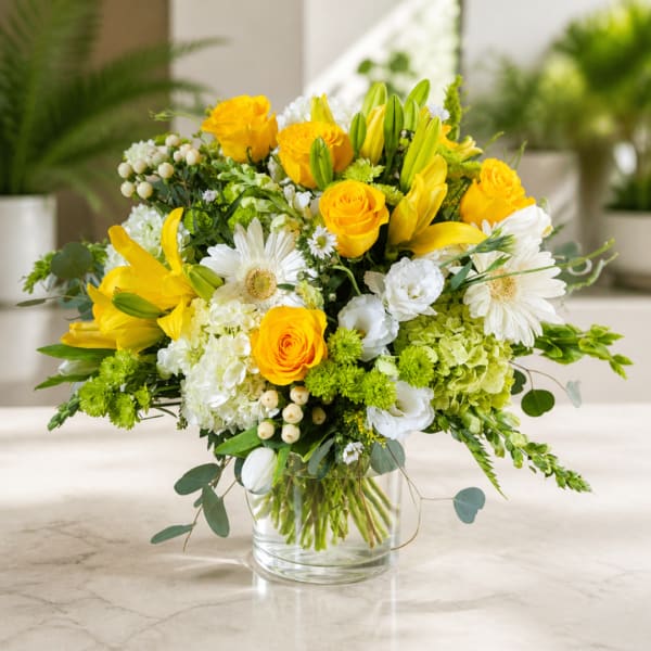 Yellow roses and white daisies arranged in a clear glass vase
