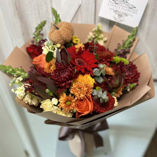 Bouquet of red, orange, and cream flowers wrapped in brown paper